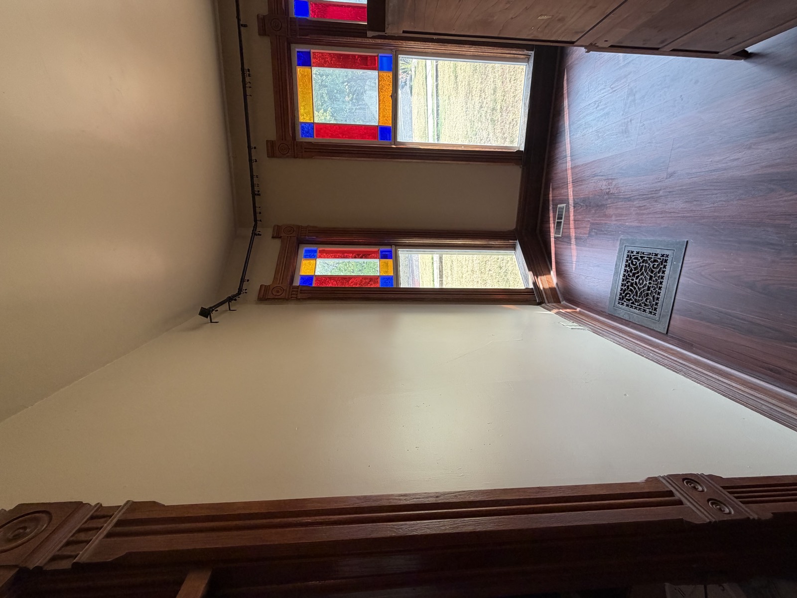 After: room repainted warm beige with original stained-glass windows and wood trim