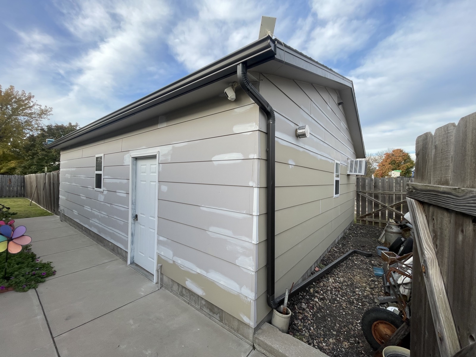 Before: detached garage with patched, primed siding